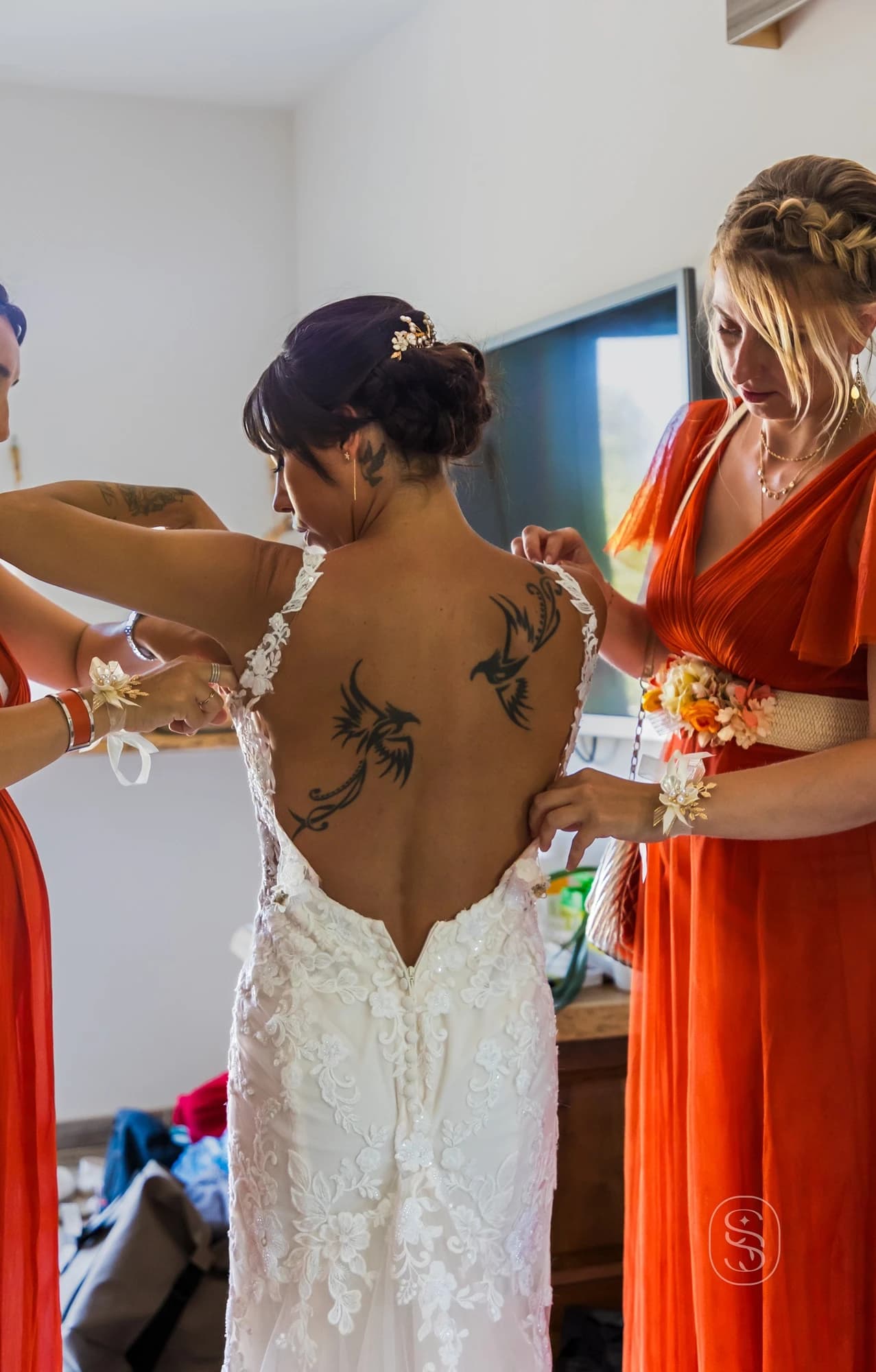 Reportage photo des préparatifs du mariage, capture des détails de l'habillage de la mariée dans une ambiance feutrée.