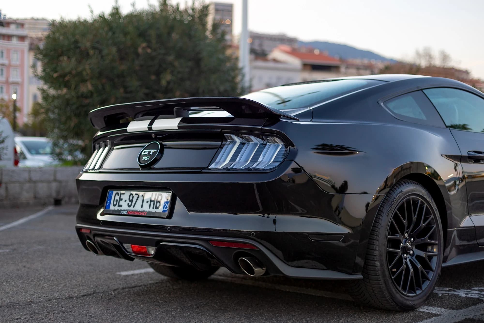 Photographie de détails d'une voiture de collection Ford Mustang, focus sur les badges et les finitions chromées.